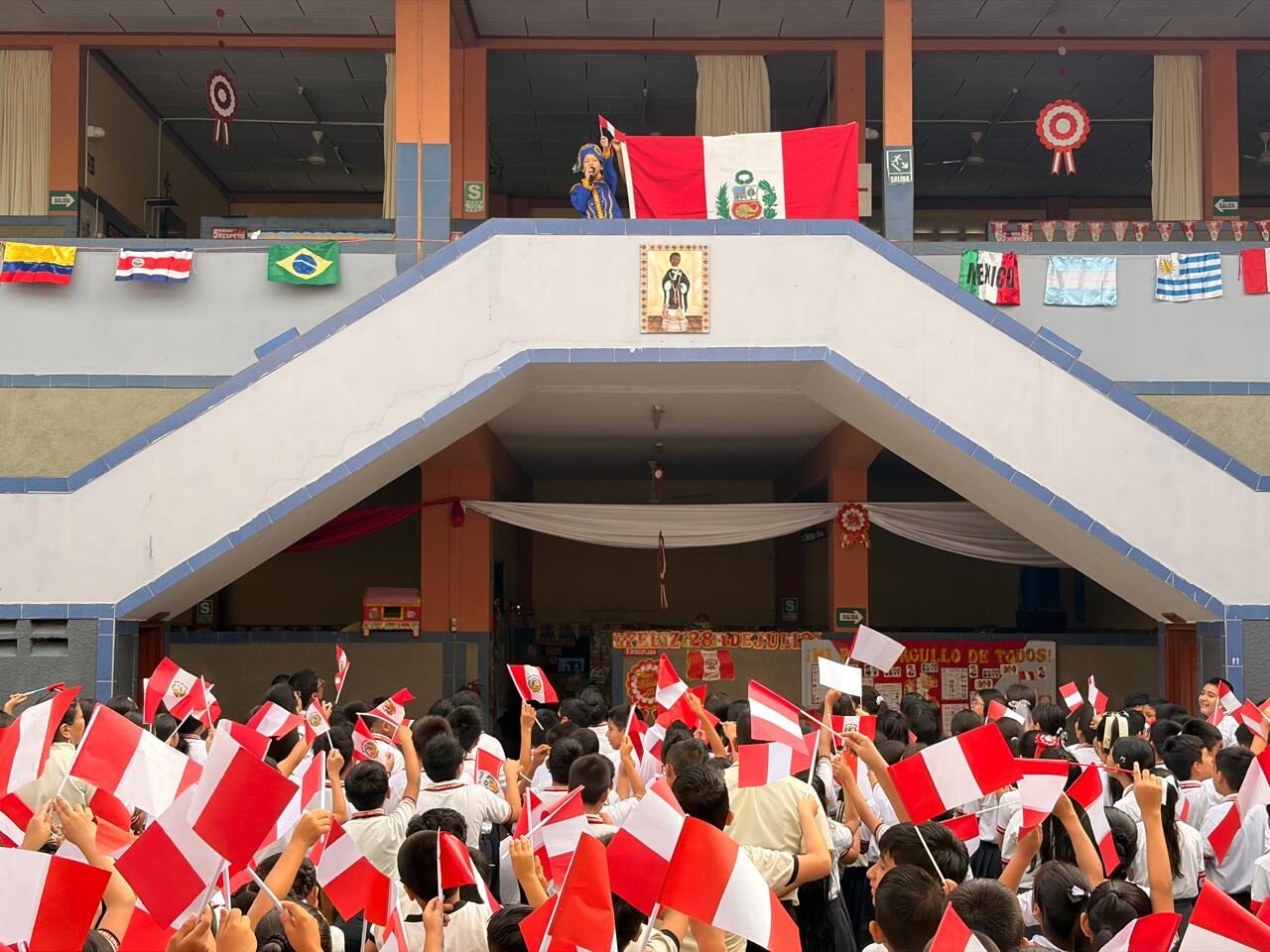 Estudiantes celebrando Fiestas Patrias con banderas del Perú